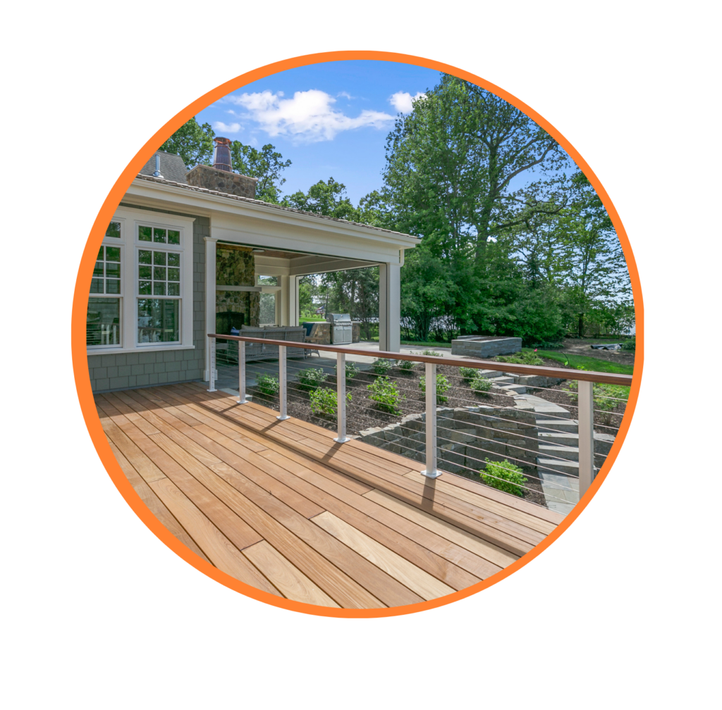 outside deck to a pastel green home during the springtime with tall green trees in the backyard